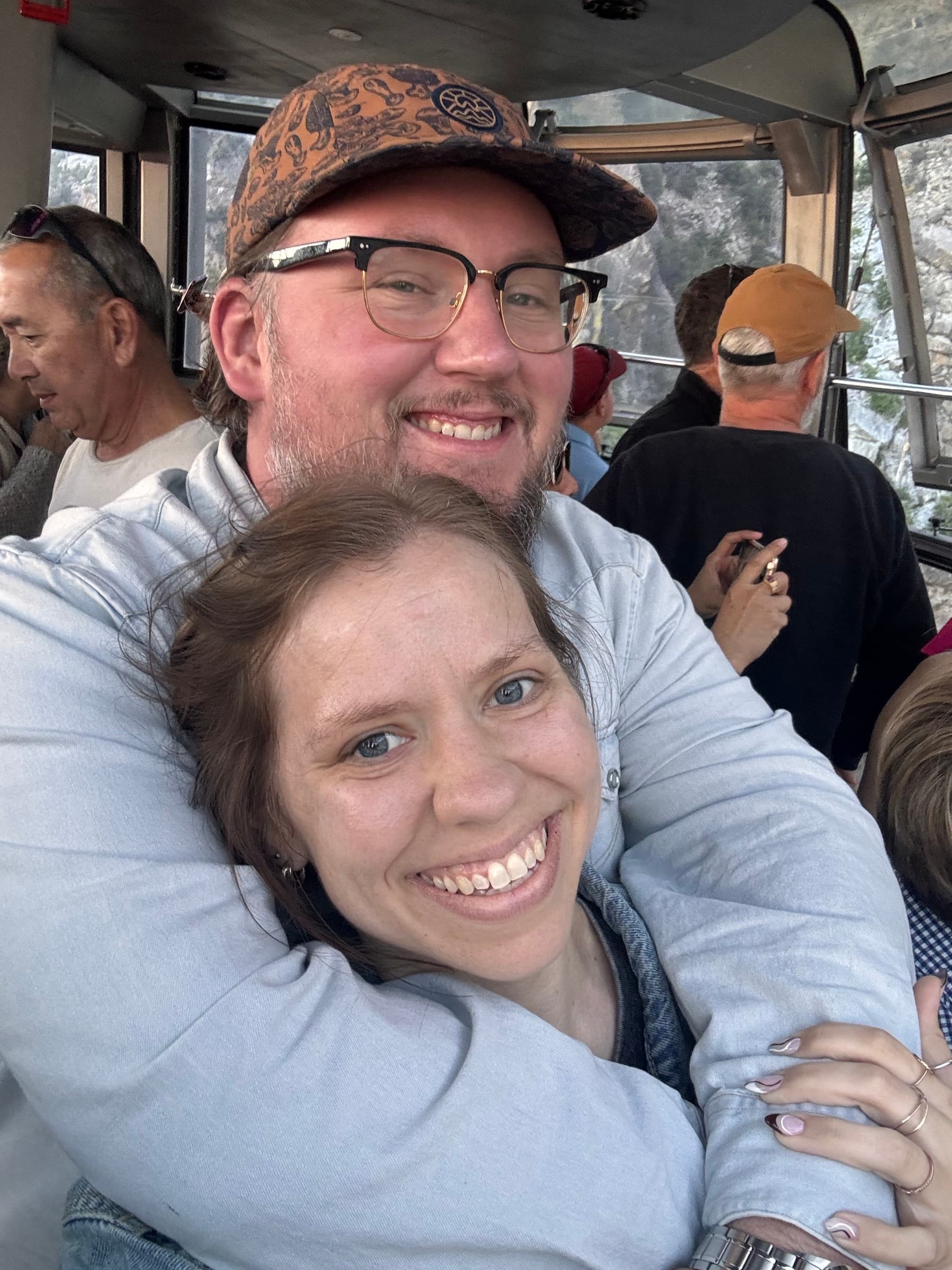 Kate and Matt embracing inside a windowed cabin.